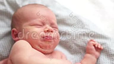 在床上哭泣的新生婴儿的特写肖像。 一个两周大的婴儿从绞痛中醒来。 新生儿的梦想